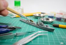 Image of person painting scale model ship, as part of a blog about how to paint model kits.
