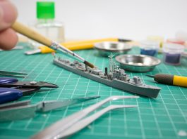 Image of person painting scale model ship, as part of a blog about how to paint model kits.