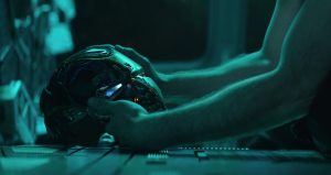 Detail of a man's hand holding Iron Man's helmet in the dark.