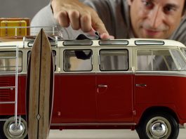 VW Bulli model seen on top of a table with a human hand next to it for scale.